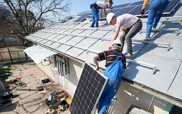 ouvrier qui pose un panneaux solairesur un toit