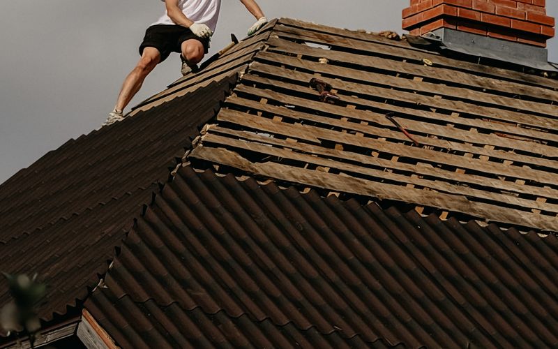 Couvreur casqué réparant la toiture d'une maison en briques