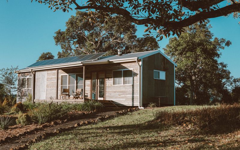 Maison à ossature bois équipée de panneaux solaires, entourée d'arbres