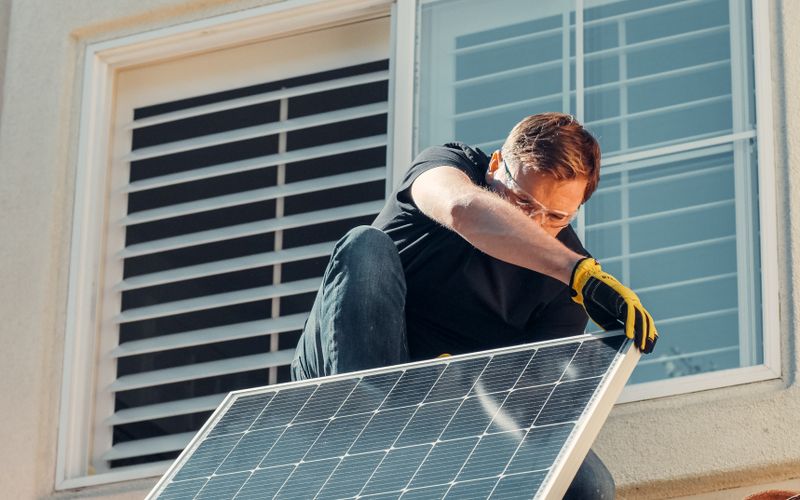 Technicien posant un panneau solaire sur le toit d'une maison