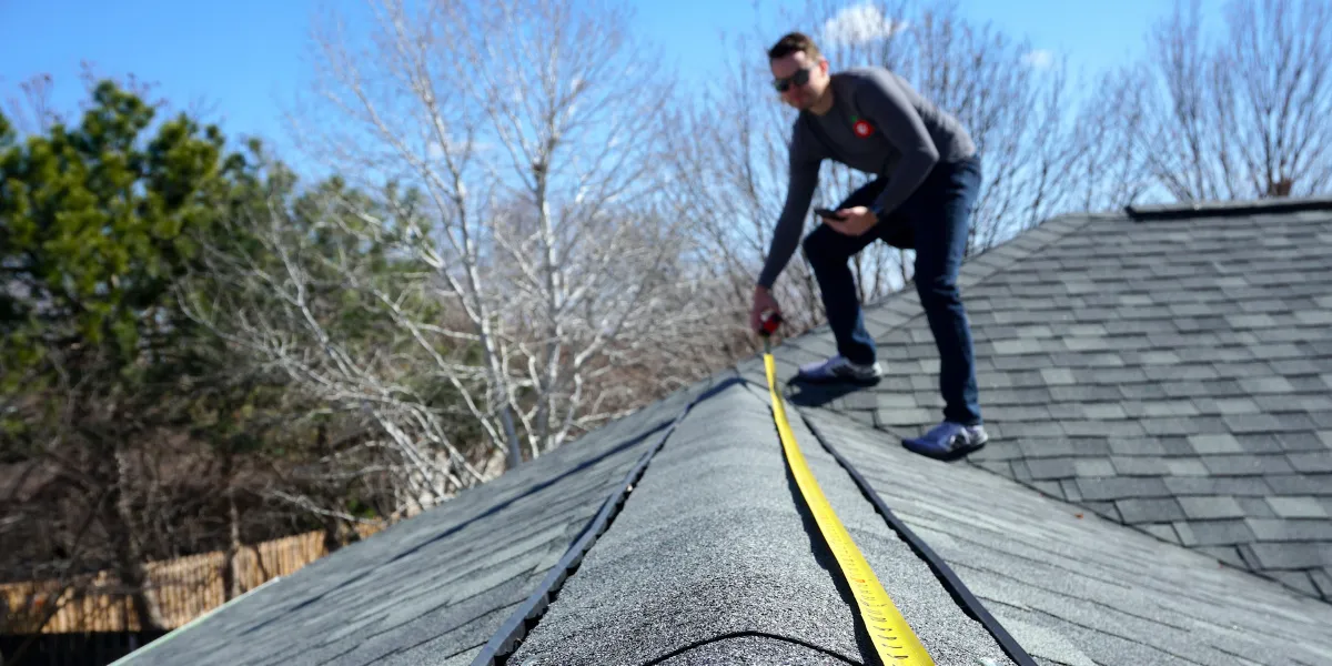 Couvreur installant une bâche de protection sur une toiture endommagée